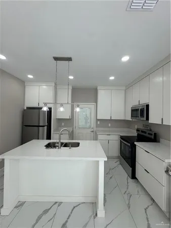 a kitchen with stainless steel appliances a sink a stove a microwave a center island and chairs
