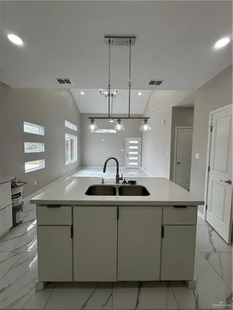 a kitchen with kitchen island granite countertop a sink and white cabinets