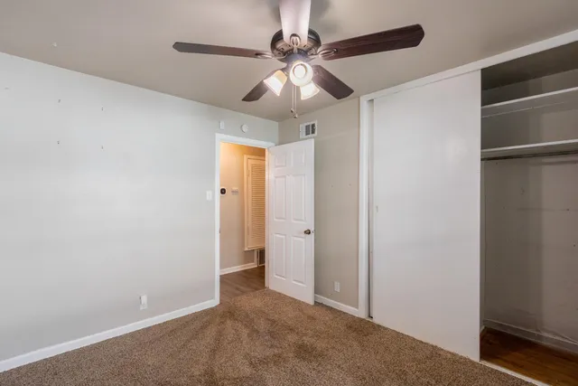 an empty room with closet and a chandelier fan