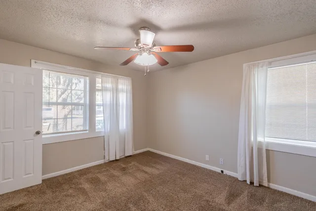 an empty room with windows and fan