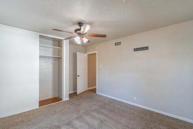 an empty room with a ceiling fan and a window