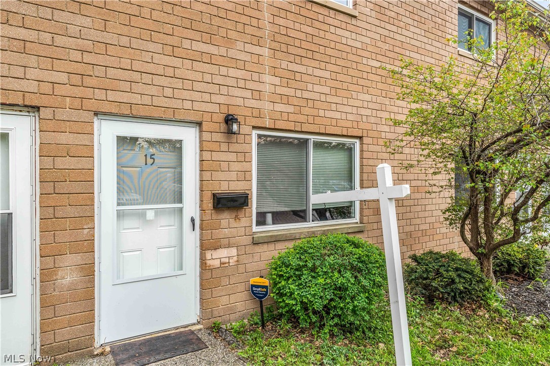 797 Babbitt Road, Unit 15 Euclid, OH 44123 - Photo 2 of 22 Brick exterior with a white storm door, black wall-mounted light fixture, and manicured landscaping