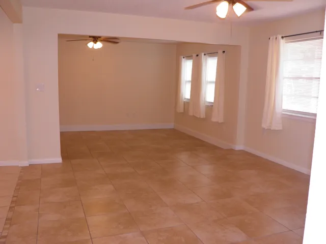 an empty room with windows and fan