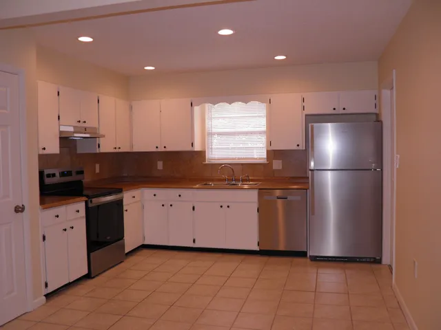 a kitchen with a refrigerator and white cabinets