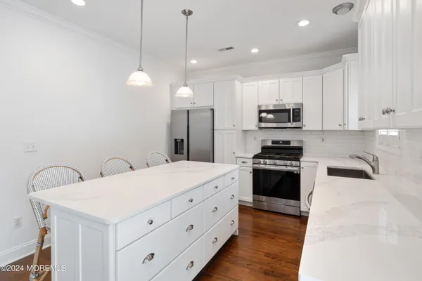 a kitchen with stainless steel appliances a stove a sink a refrigerator a stove a microwave and a refrigerator