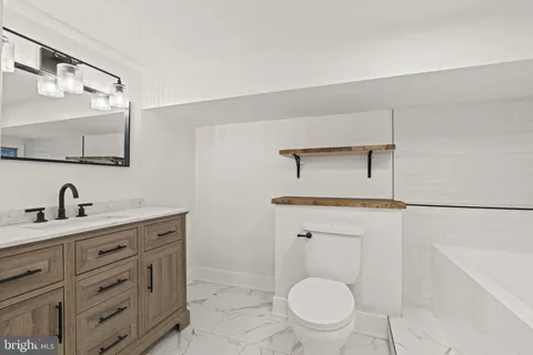 a bathroom with a toilet a sink a mirror and vanity