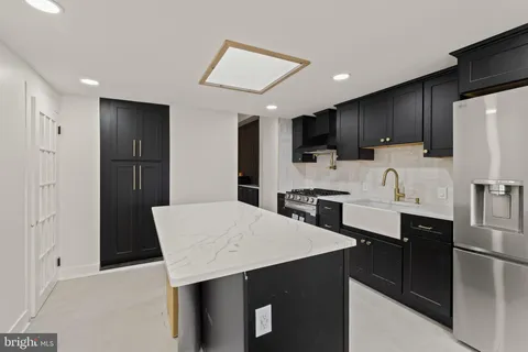 a kitchen with stainless steel appliances kitchen island granite countertop a refrigerator a sink a stove a microwave and cabinets