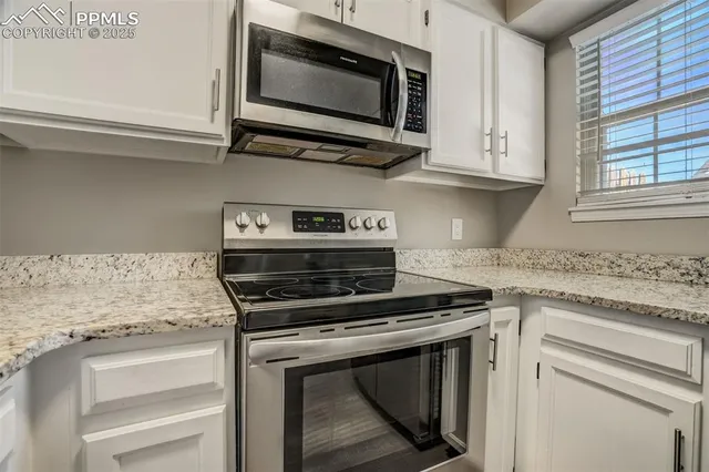 a kitchen with stainless steel appliances granite countertop white cabinets and a stove top oven