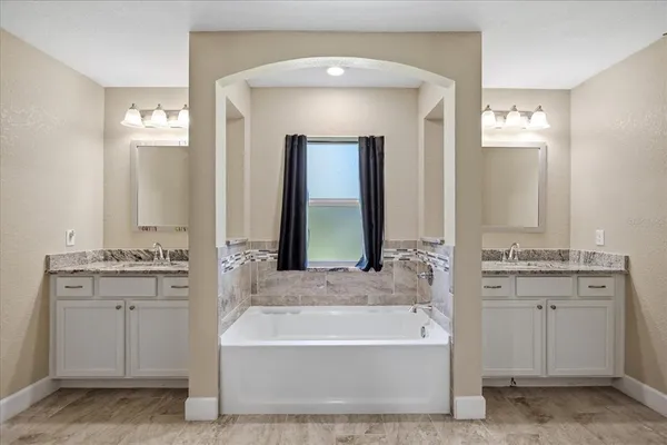 a bathroom with a tub a double vanity sink and mirror
