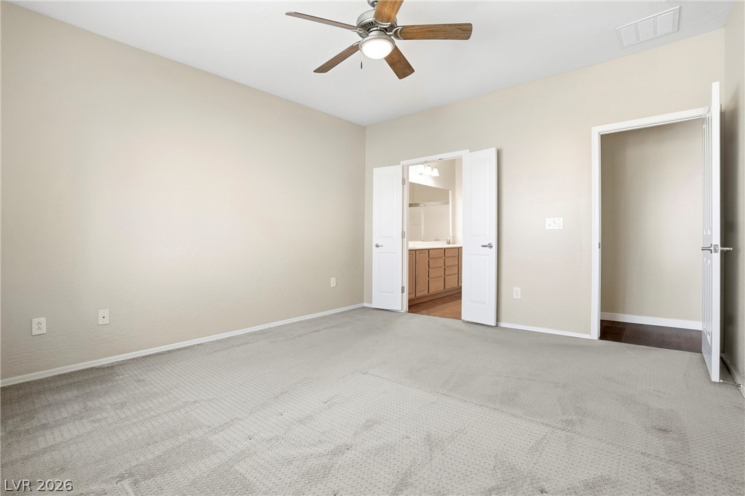 2541 Darda Street Henderson, NV 89044 - Photo 17 of 26 This spacious primary bedroom features soft carpet flooring, a ceiling fan, and convenient access to the primary bathroom.