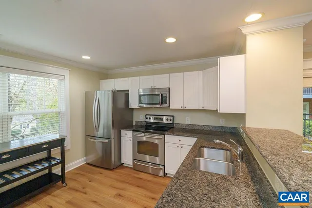 a kitchen with stainless steel appliances granite countertop a refrigerator a stove and a sink with wooden floor