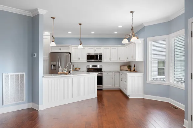 a large white kitchen with lots of counter space a sink appliances and cabinets