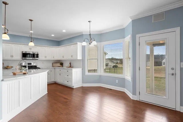 a large kitchen with white cabinets and wooden floor