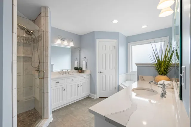 a spacious bathroom with a granite countertop sink a mirror and a shower