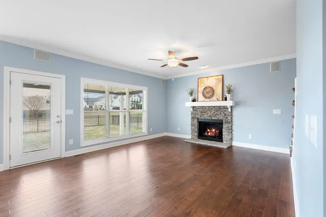 a view of an empty room with wooden floor fireplace and a window