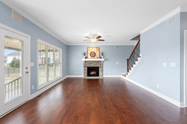 a view of an empty room with wooden floor fireplace and a window