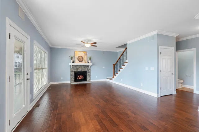 a view of an empty room with wooden floor fireplace and a window