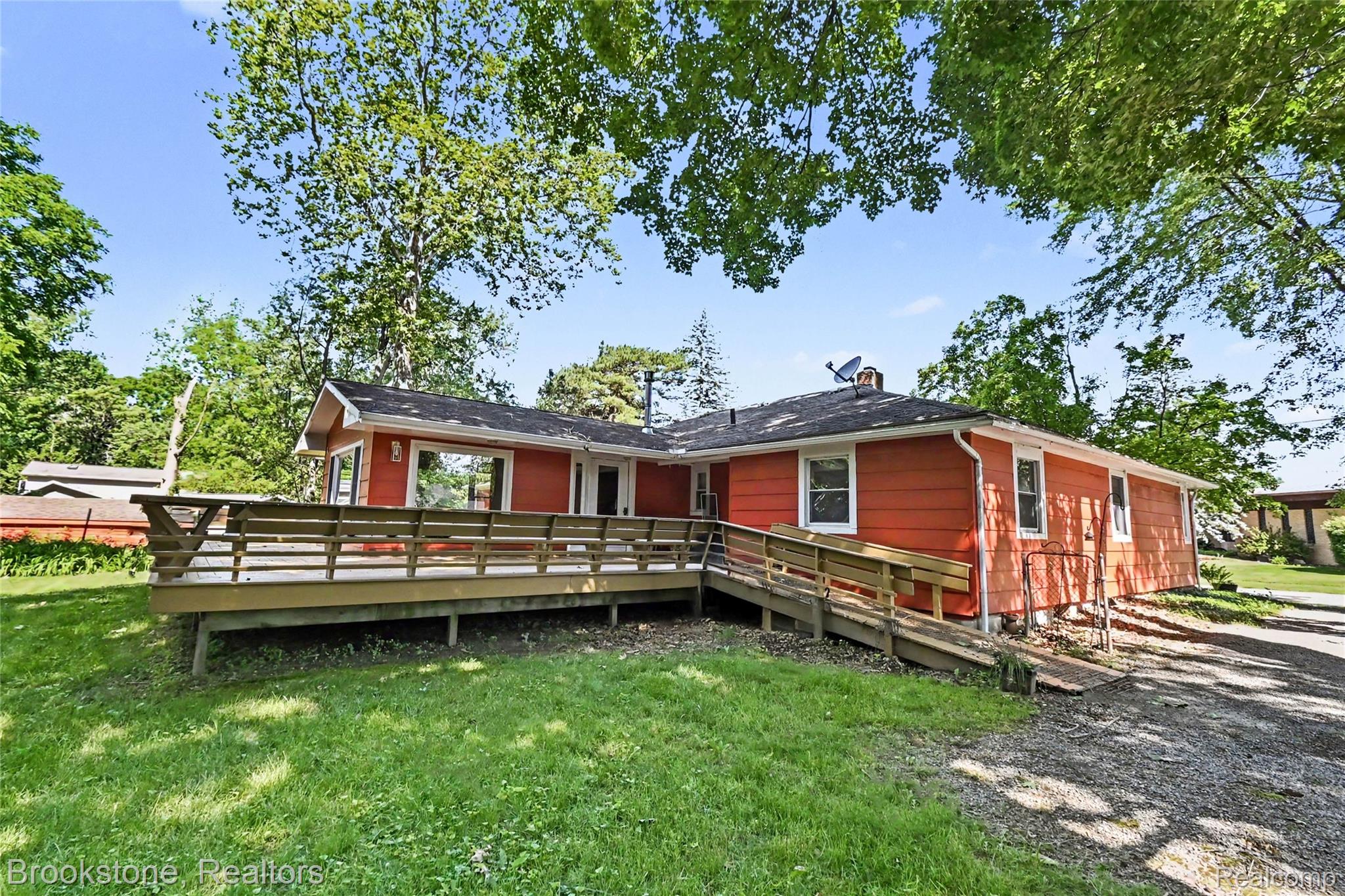 416 East Maple Street Mason, MI 48854 - Photo 16 of 18 Expansive exterior deck featuring a ramp for access, red siding, and white trim windows