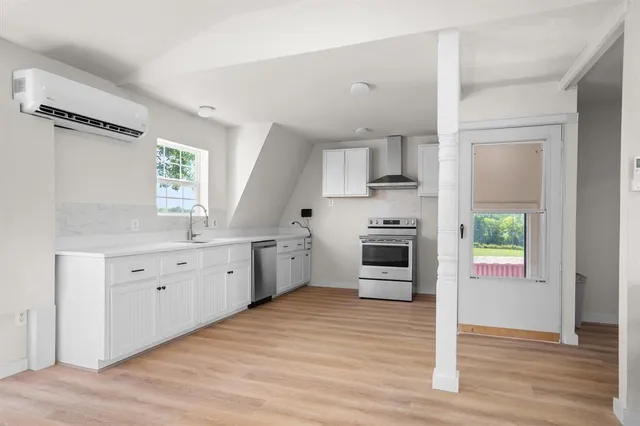 a kitchen with granite countertop a refrigerator a sink dishwasher a stove and white cabinets with wooden floor