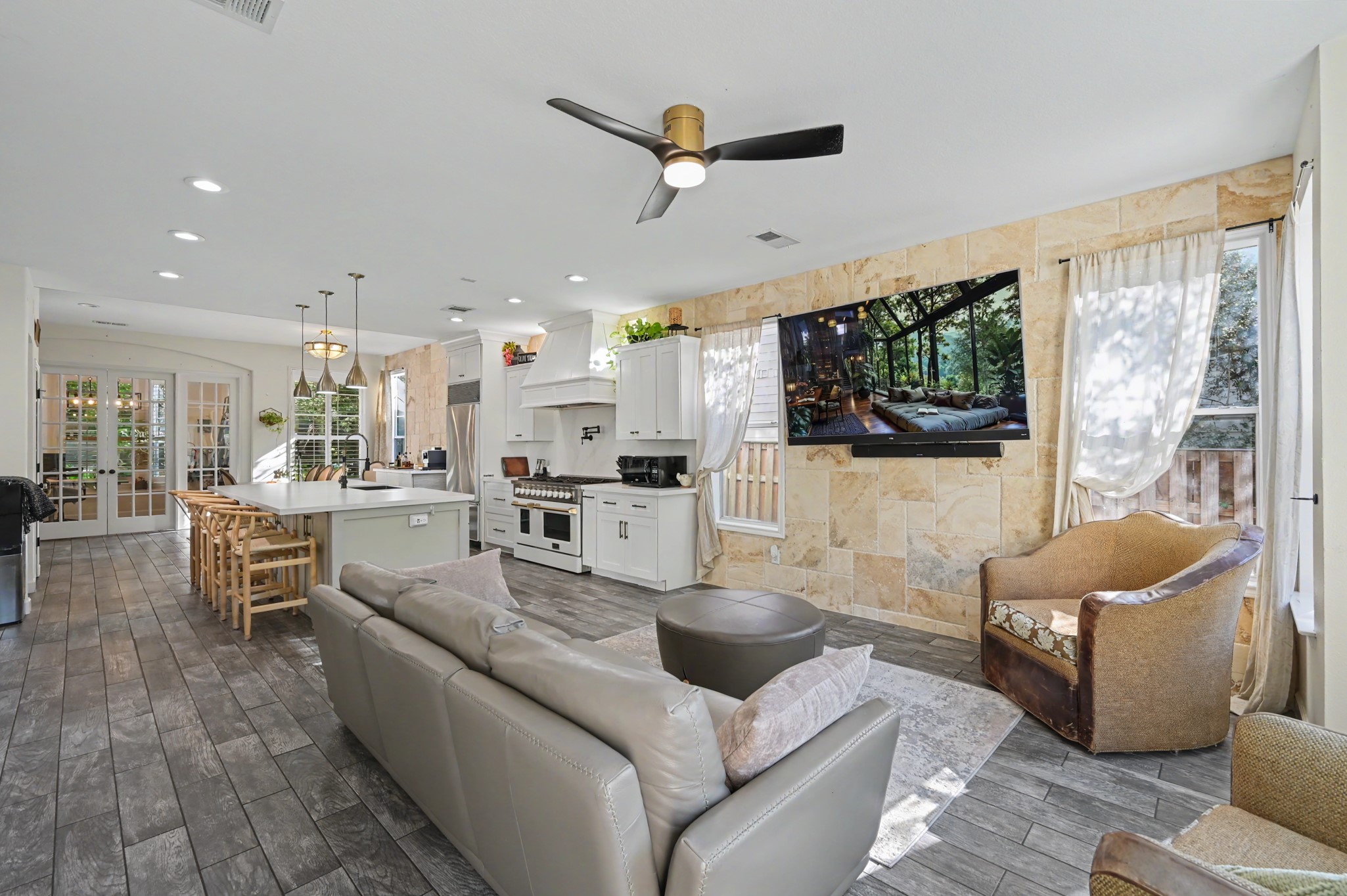 55 South Bethany Bend Circle Spring, TX 77382 - Photo 16 of 28 An inviting open-concept living space flows seamlessly into the kitchen, highlighted by a striking stone accent wall, abundant natural light, and generous space for both everyday living and entertaining.