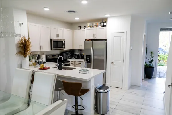 a kitchen with stainless steel appliances a refrigerator a sink a stove and white cabinets