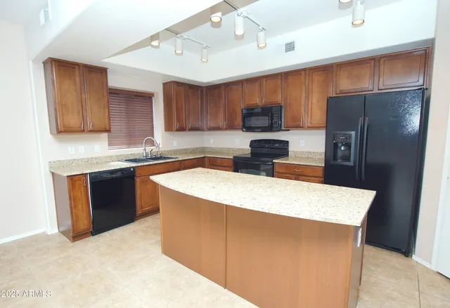a kitchen with stainless steel appliances a refrigerator a sink a stove a microwave and wooden cabinets