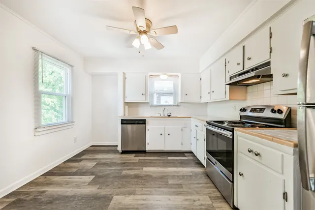a kitchen with stainless steel appliances granite countertop a sink a stove cabinets and wooden floor