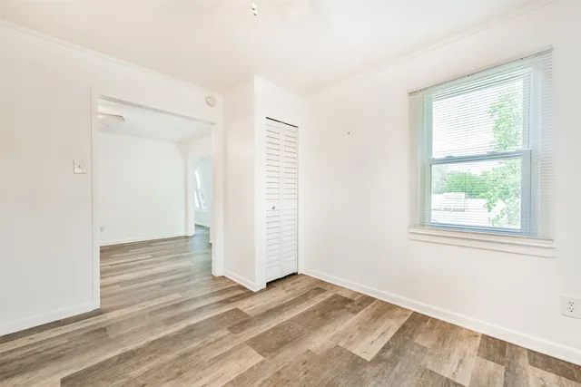 an empty room with wooden floor cabinet and windows