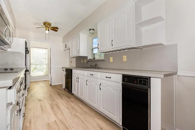 a kitchen with granite countertop a sink cabinets stainless steel appliances and a counter top space