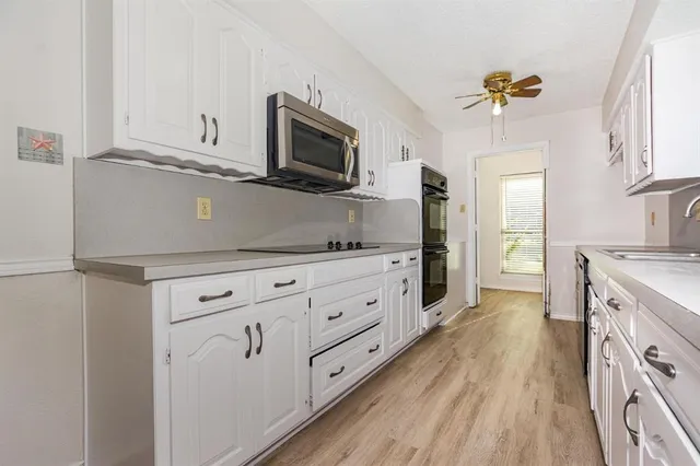 a kitchen with stainless steel appliances white cabinets and wooden floor
