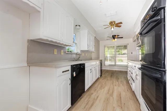 a kitchen with a sink a stove cabinets and a wooden floor