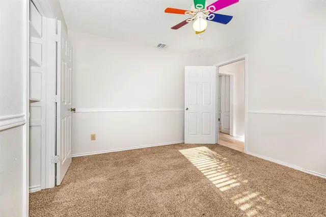 a view of a room with a ceiling fan and a refrigerator