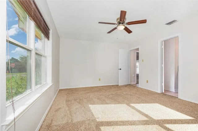 an empty room with a window and a fan