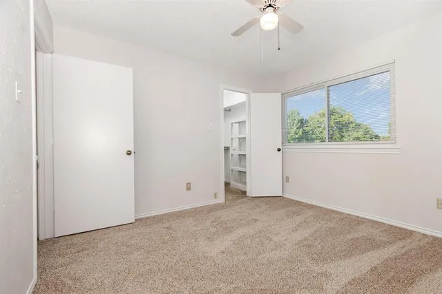 an empty room with a ceiling fan and a window