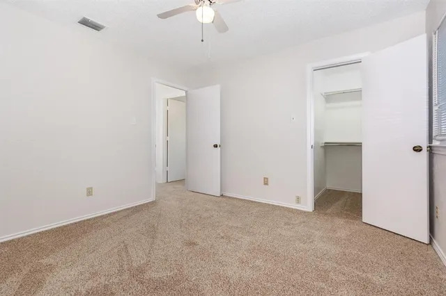an empty room with a window and a ceiling fan