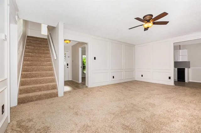 a view of an empty room with stairs and a ceiling fan