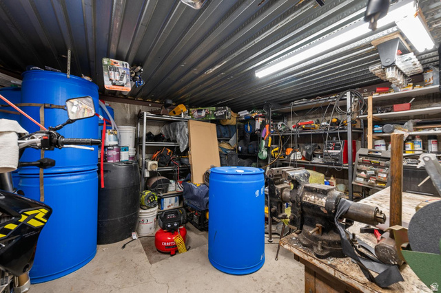708 Eagle Rdg Drive Bountiful, UT 84010 - Photo 59 of 69 Workroom featuring a corrugated metal ceiling, concrete flooring, built-in shelving, and workbench with a mounted vise
