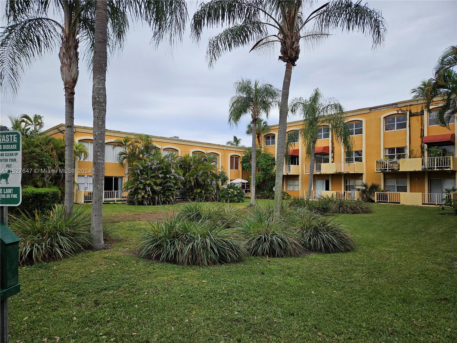 a view of a garden with a building and palm trees