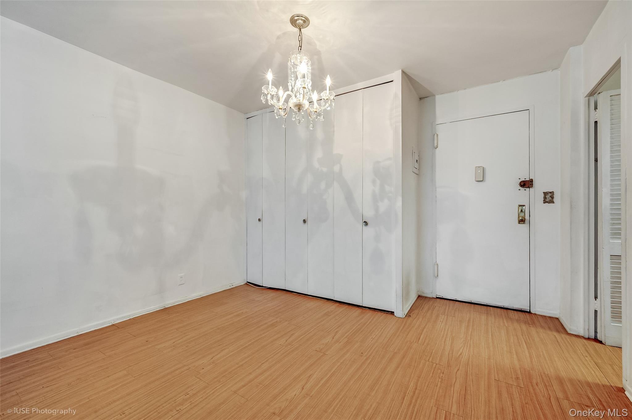 39-65 52nd Street, Unit 2H Queens, NY 11377 - Photo 5 of 18 wooden floor in an empty room with a chandelier