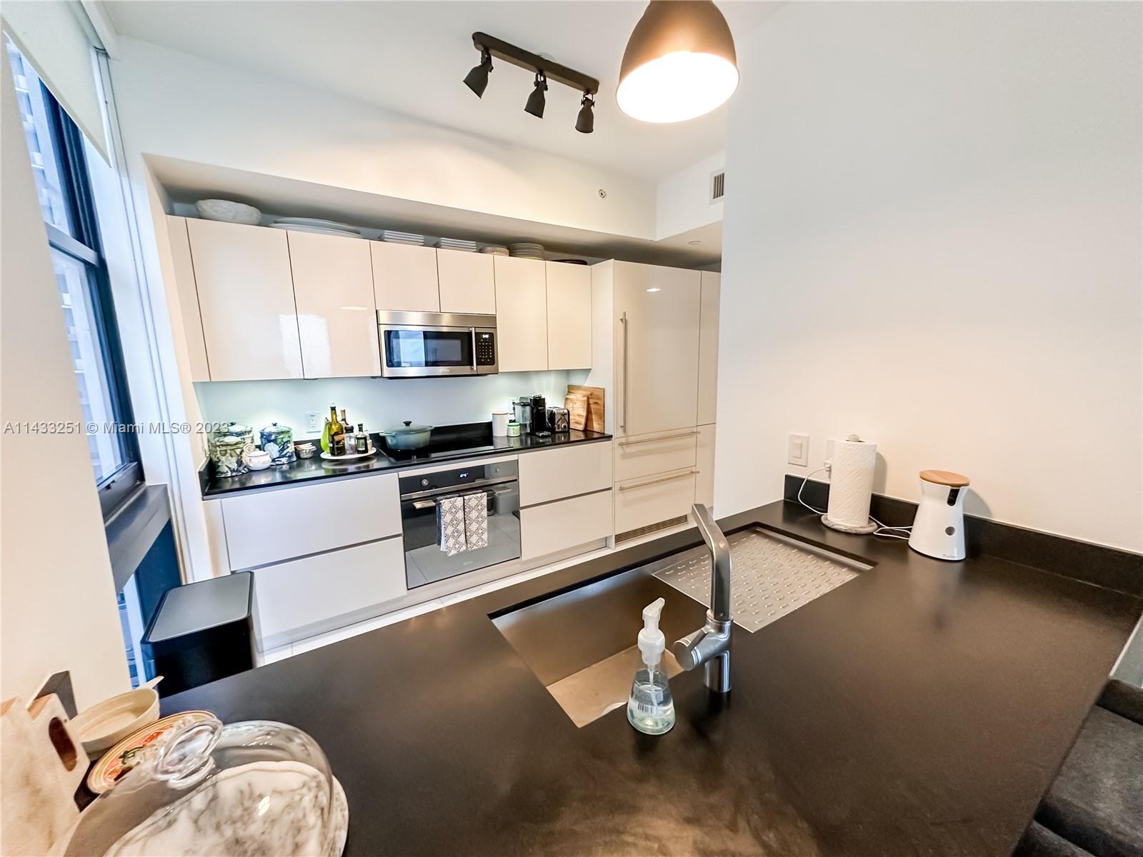 1010 Brickell Avenue, Unit 2505 Miami, FL 33131 - Photo 11 of 38 a kitchen with a sink a stove and chairs
