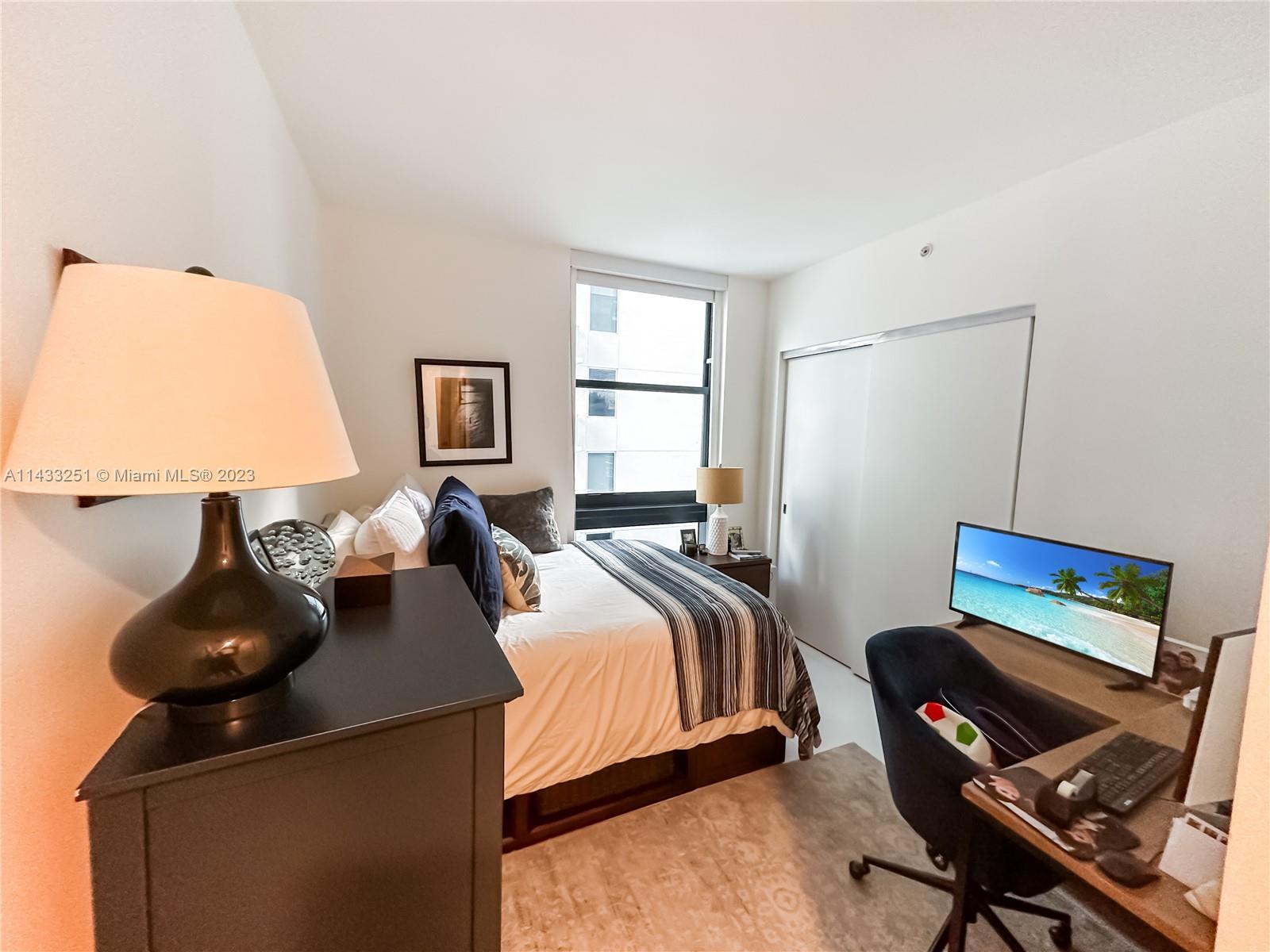 1010 Brickell Avenue, Unit 2505 Miami, FL 33131 - Photo 21 of 38 a bedroom with a bed and a computer on a desk next to a window