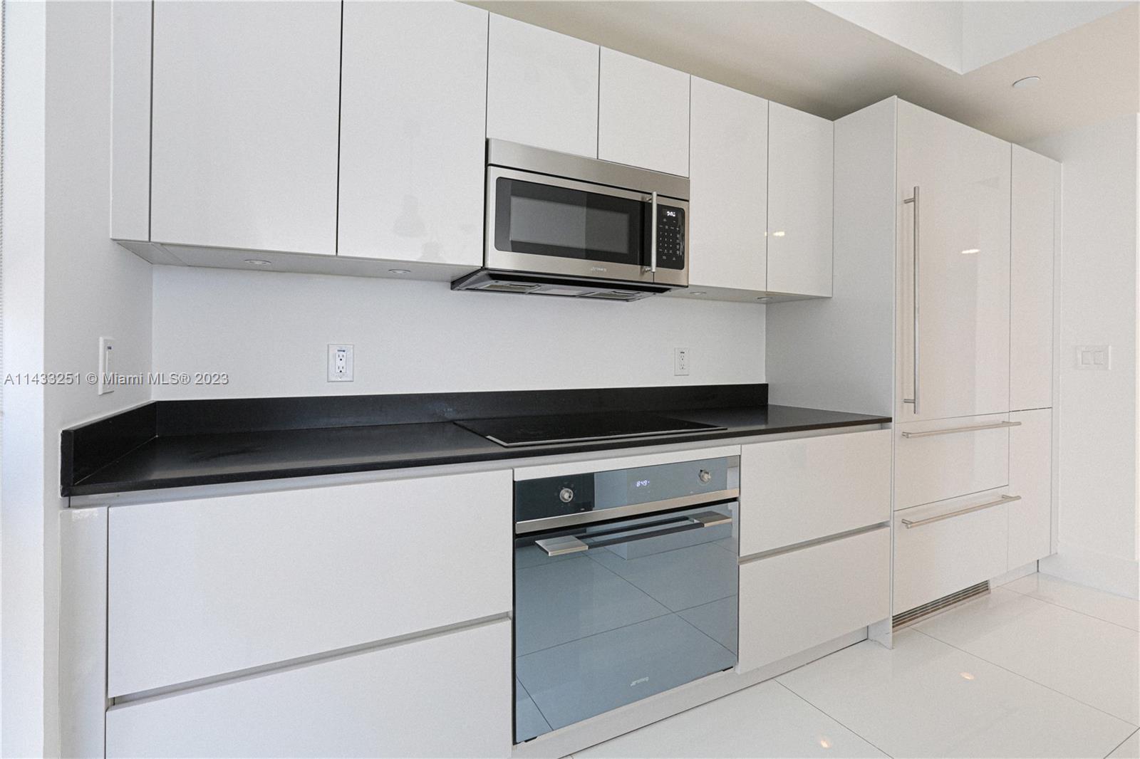 1010 Brickell Avenue, Unit 2505 Miami, FL 33131 - Photo 27 of 38 a kitchen with granite countertop white cabinets and stainless steel appliances