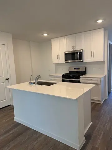 a kitchen with stainless steel appliances a sink a stove a microwave a refrigerator a sink and cabinets