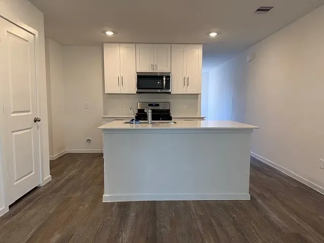 a kitchen with kitchen island a sink a stove a refrigerator and a microwave