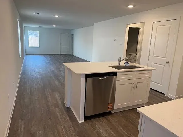a kitchen with a sink and wooden floor