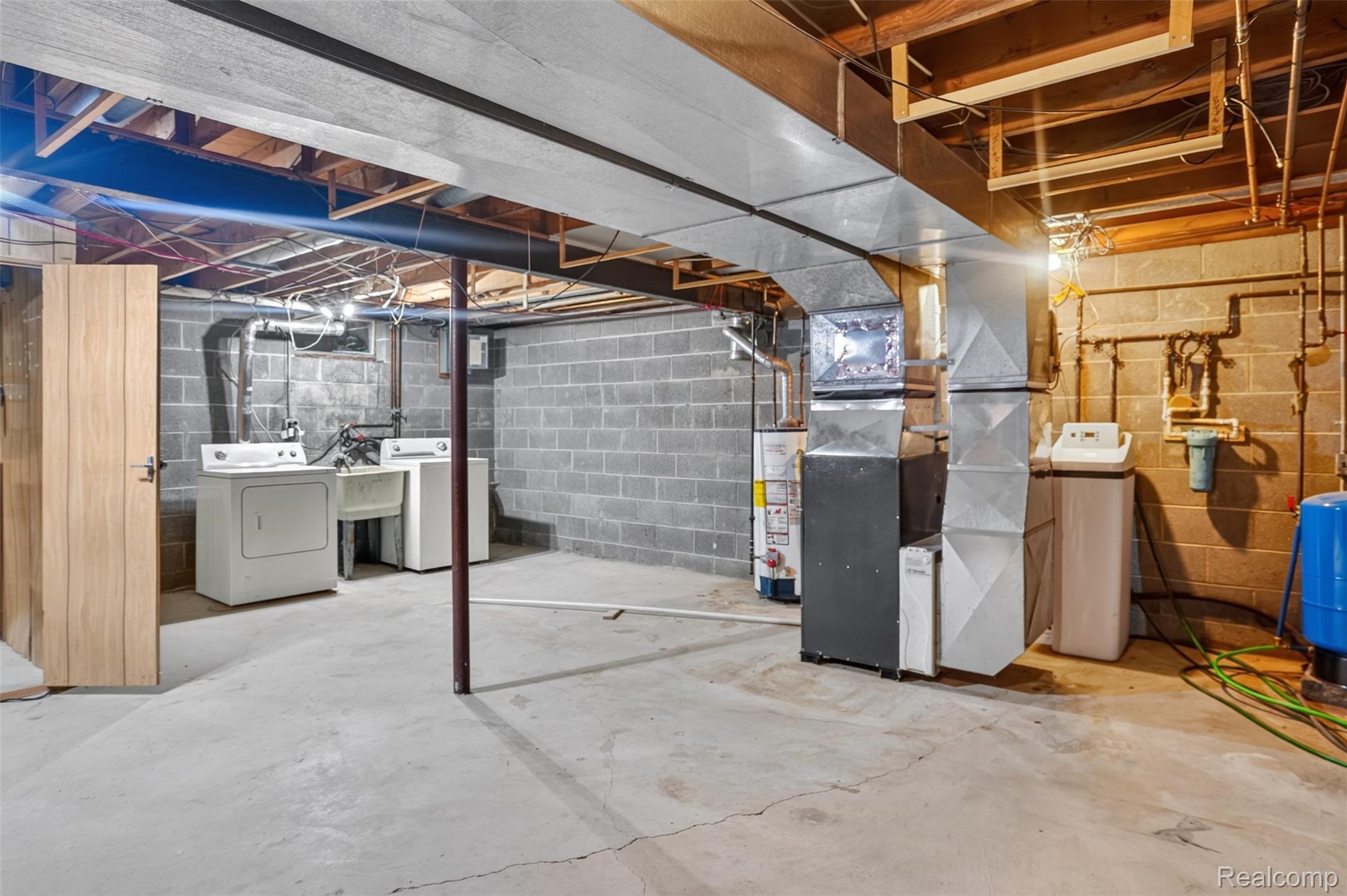 16955 English Road Manchester, MI 48158 - Photo 25 of 37 Unfinished basement featuring exposed wood ceiling joists, concrete block walls, concrete flooring, and a dedicated laundry area with utility sink