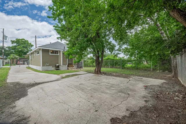a view of a house with a yard and large trees