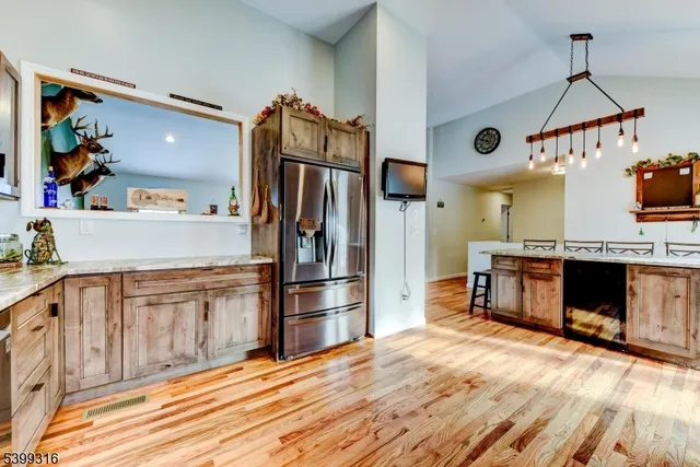 a kitchen with stainless steel appliances granite countertop a refrigerator a stove and a sink with wooden floor