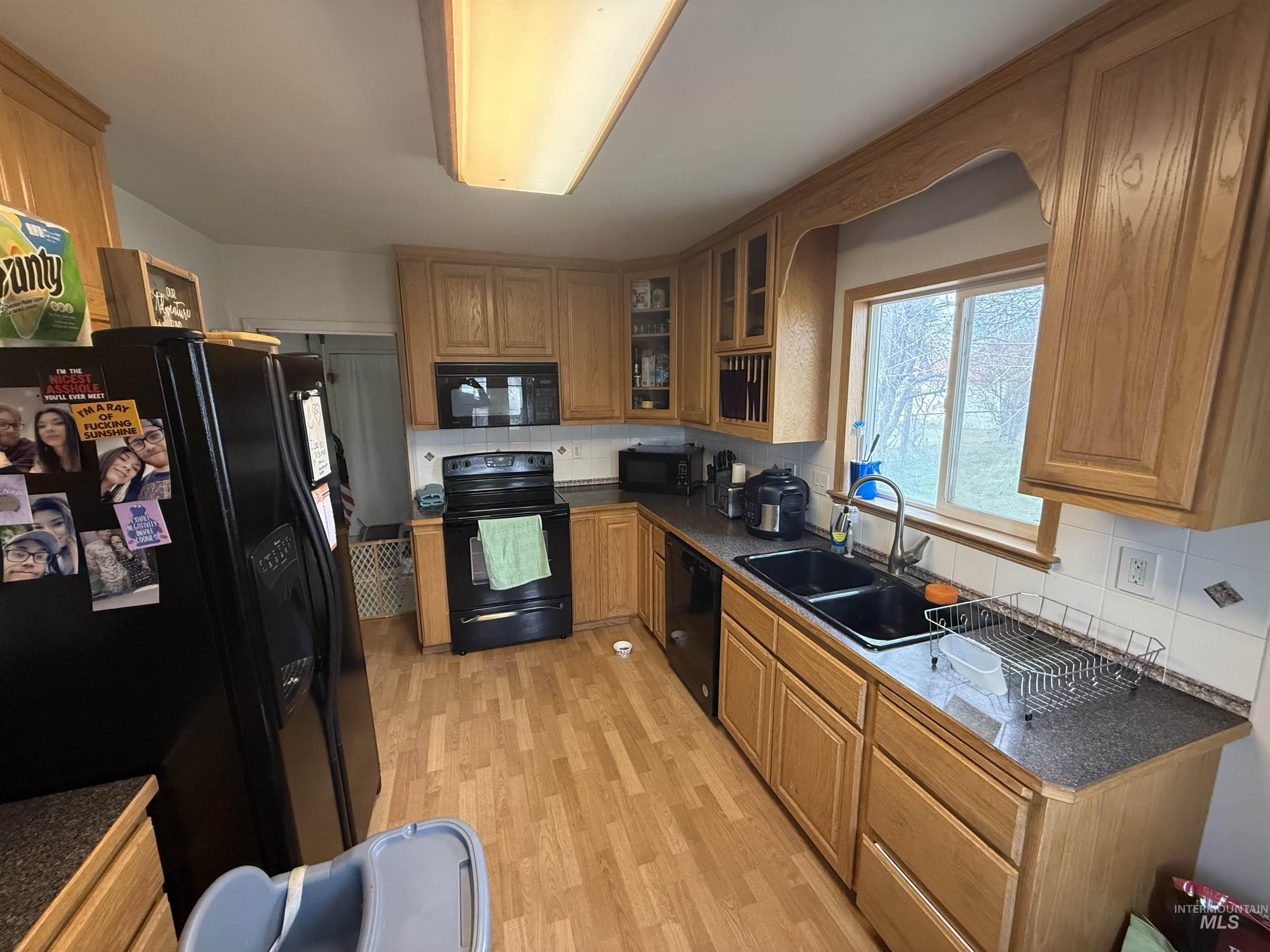 918 5th Street Rupert, ID 83350 - Photo 5 of 14 Kitchen featuring dark countertops, black appliances, glass insert cabinets, and backsplash