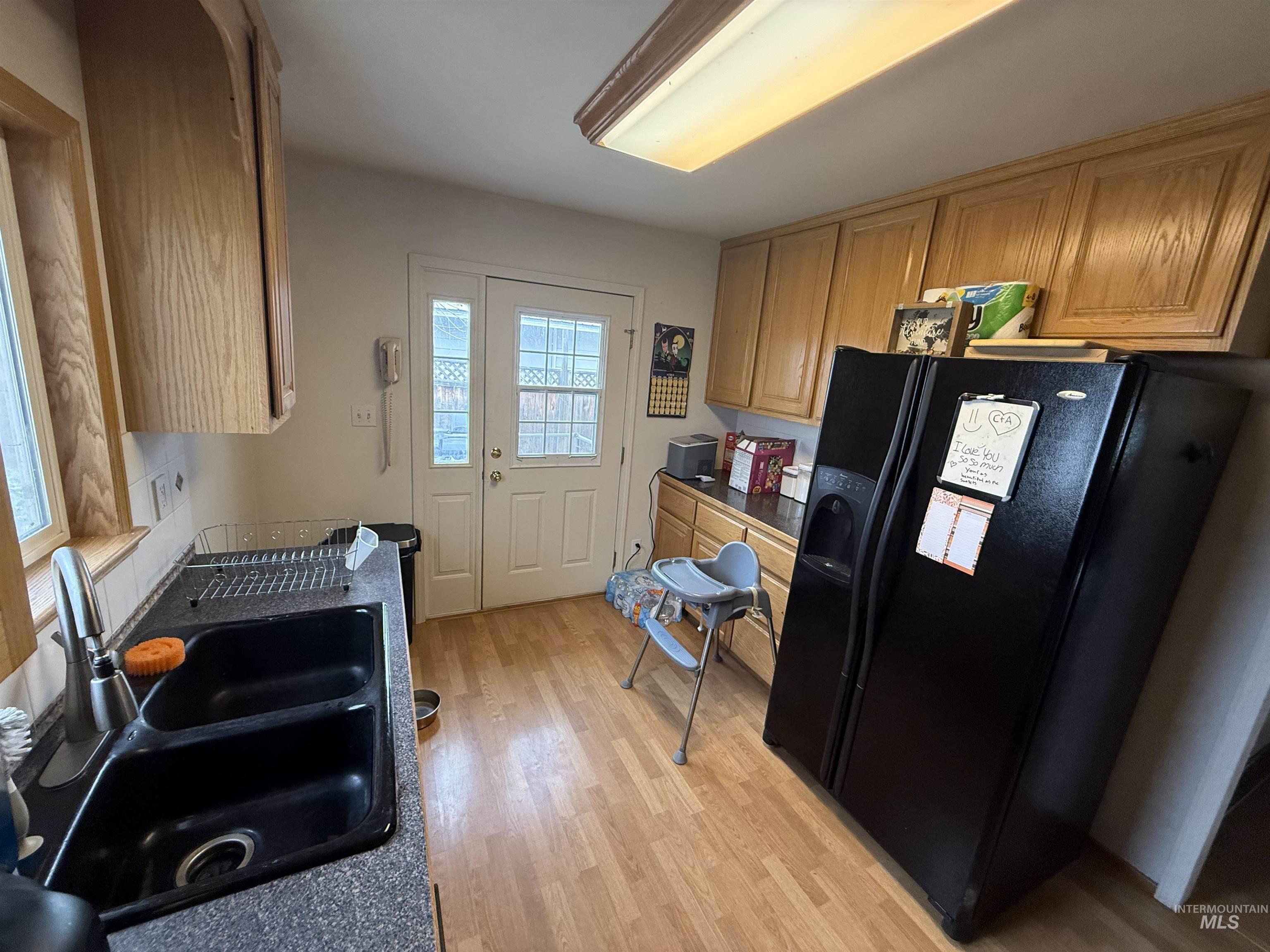 918 5th Street Rupert, ID 83350 - Photo 6 of 14 Kitchen featuring black refrigerator with ice dispenser, wood finish cabinetry, dark countertops, and light wood-style flooring